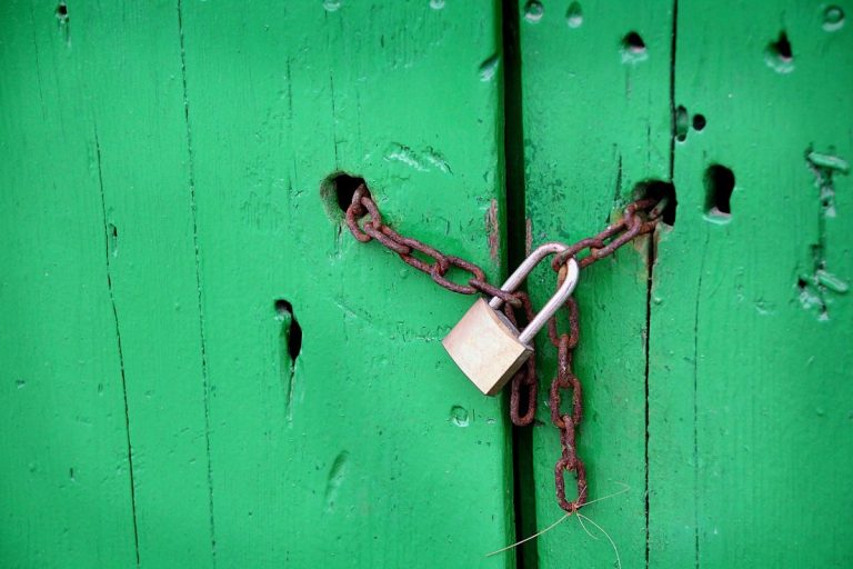 Minimum promoter contribution IPO lock-in concept: a padlock and chain securing a green wooden door