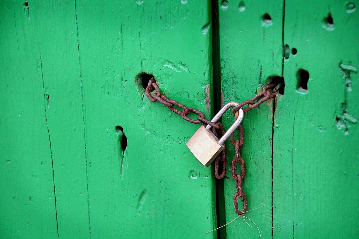 Minimum promoter contribution IPO lock-in concept: a padlock and chain securing a green wooden door