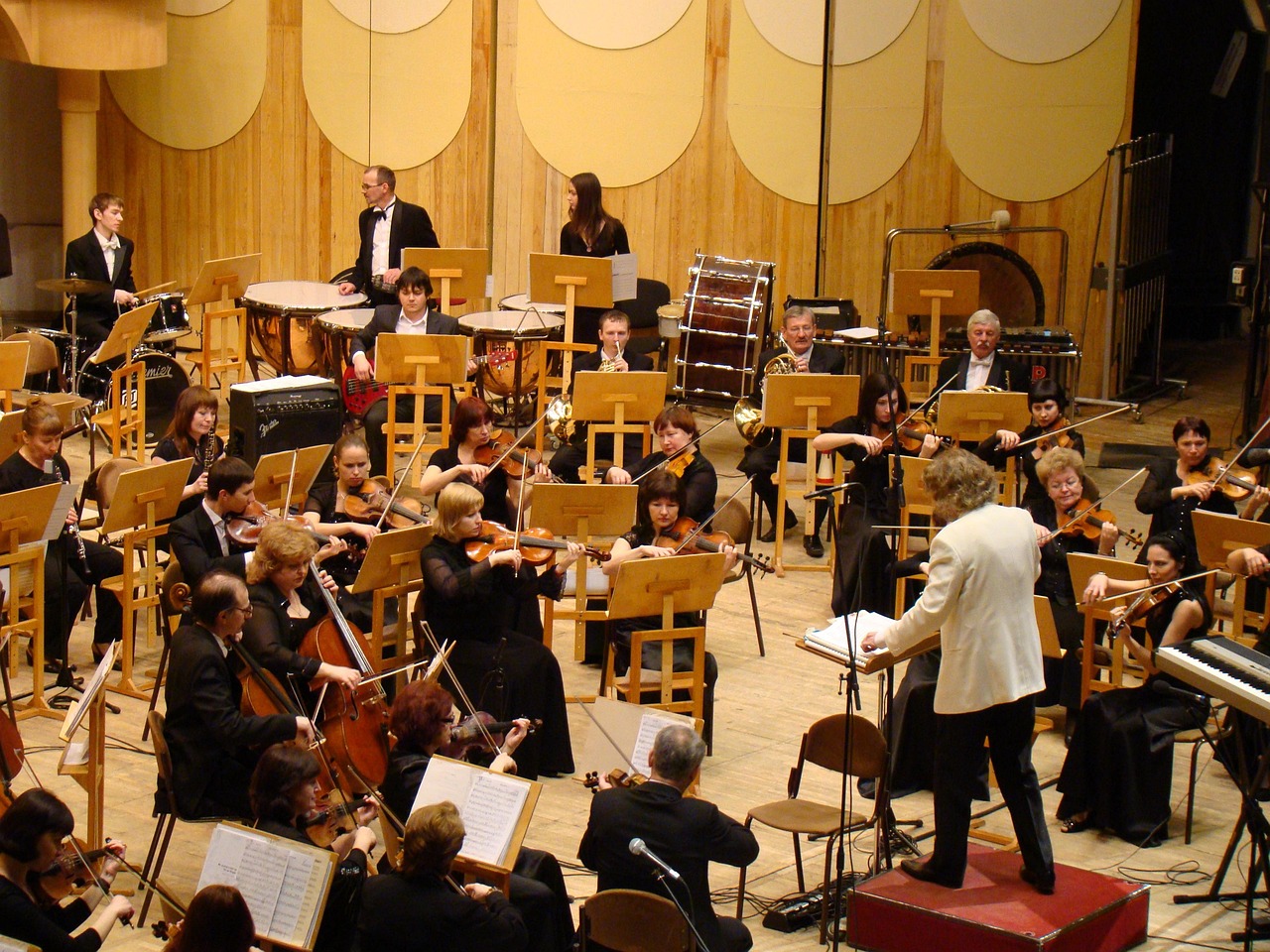 Book running lead manager: a conductor in a white jacket leading a symphony orchestra on stage