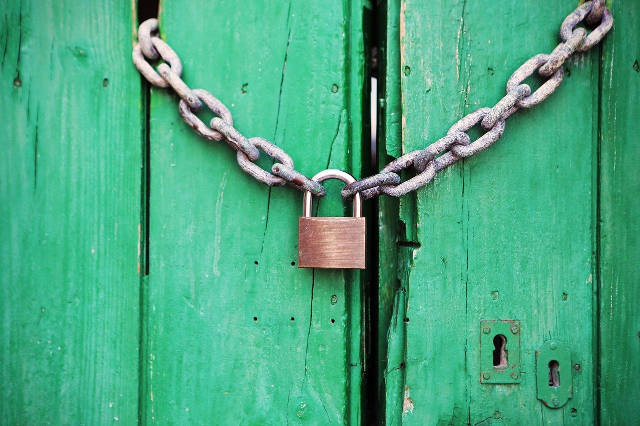 Demat account freeze concept: a padlock and chain locking a green wooden door shut