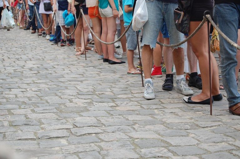 Retail individual investor quota IPO concept: people waiting in a roped queue on a cobbled street