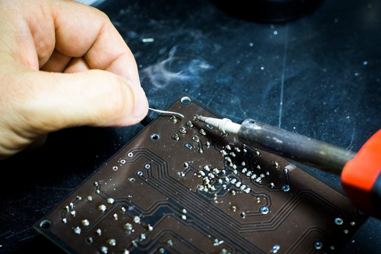 Avalon Zollner joint venture: a technician hand-soldering a printed circuit board, the kind of PCBA work the JV will do