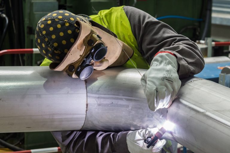 Venus Pipes pipe spooling: a welder joining two sections of stainless-steel pipe in a factory