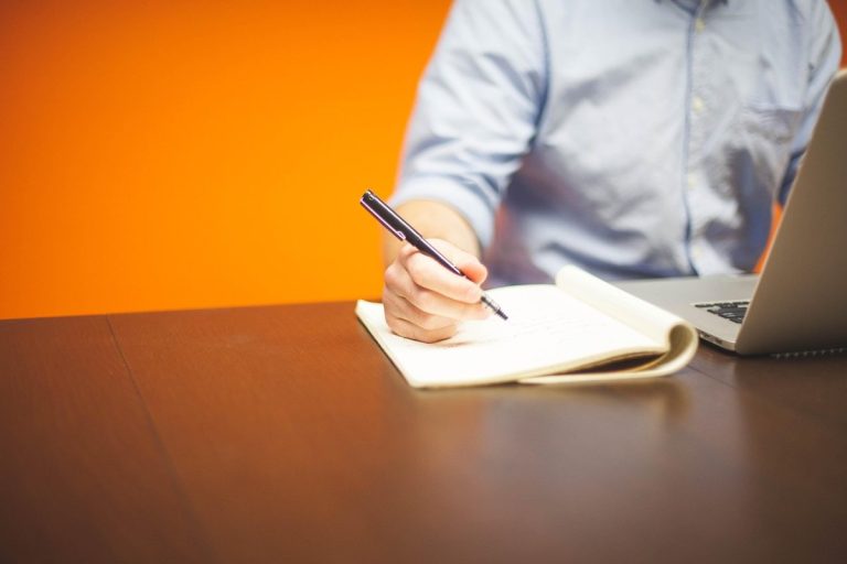 Sweat equity shares concept: an entrepreneur writing notes beside a laptop at a desk