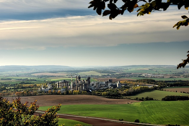 ACC Q2 results: a cement plant with silos and chimneys set among green fields