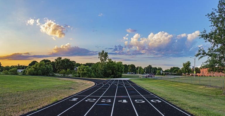 Accelerator oscillator: an empty running track with numbered lanes at the start line under an evening sky