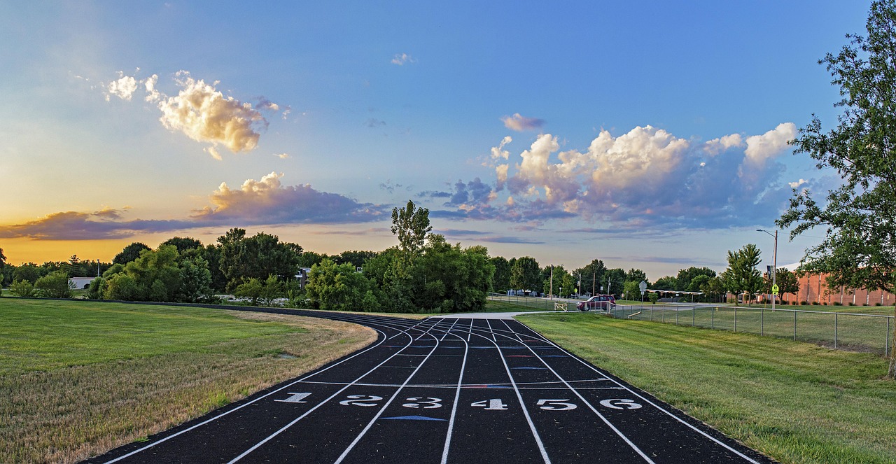 Accelerator oscillator: an empty running track with numbered lanes at the start line under an evening sky