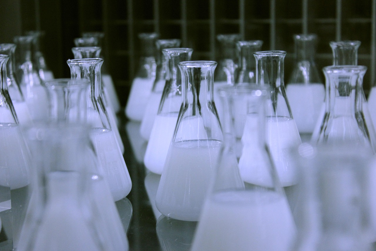 Acutaas Chemicals Q2 results: rows of glass Erlenmeyer flasks filled with white liquid in a chemistry lab