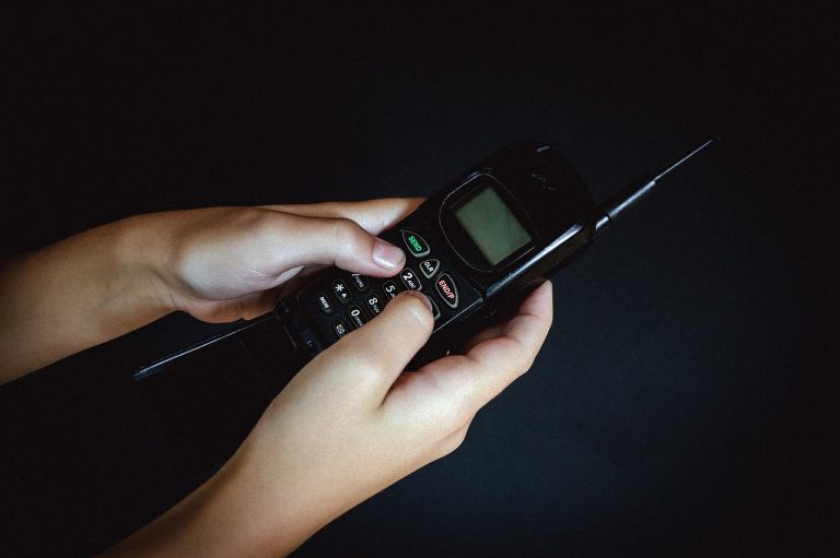 Airtel voice-only plans: hands dialling on an old keypad mobile phone against a dark background