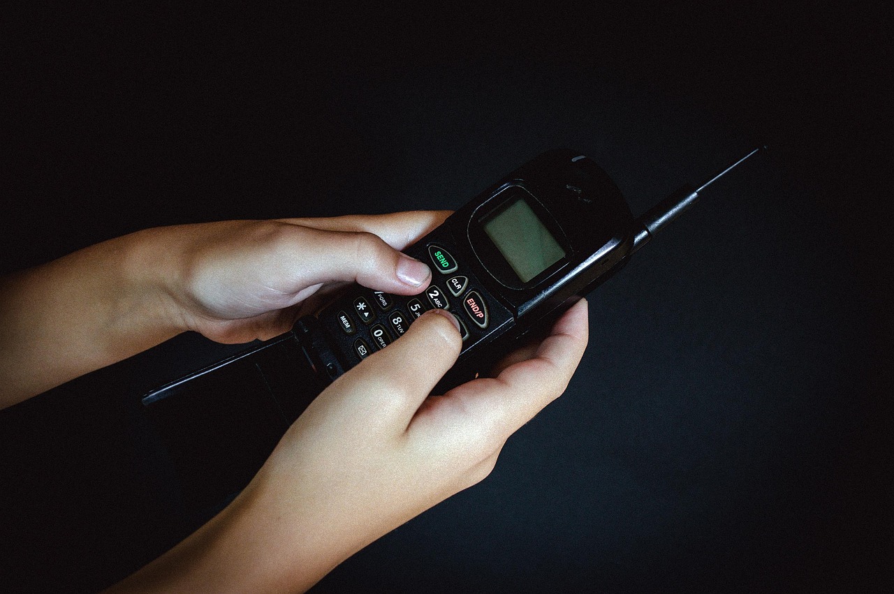 Airtel voice-only plans: hands dialling on an old keypad mobile phone against a dark background