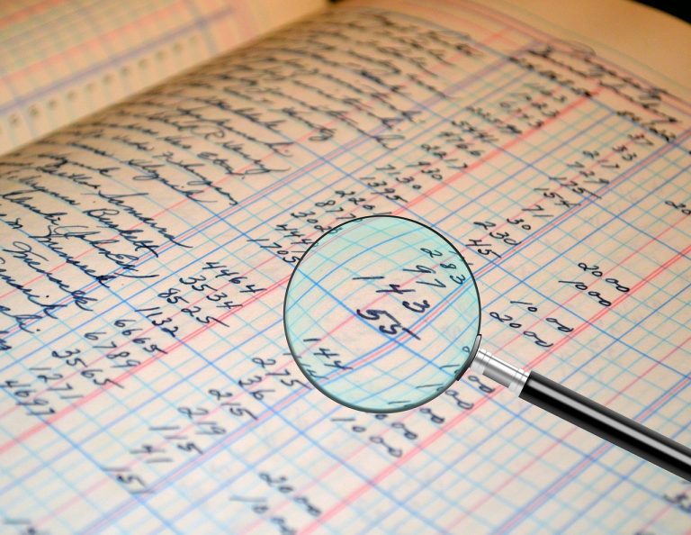 Auditor qualified opinion meaning: magnifying glass over handwritten ledger figures