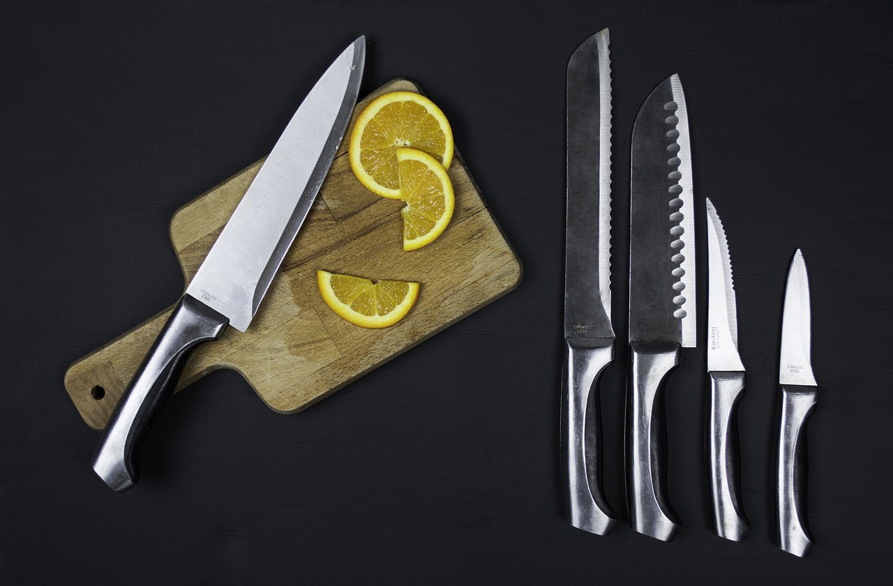 Averaging down stocks idea: a chef knife on a chopping board with orange slices beside a row of sharp kitchen knives