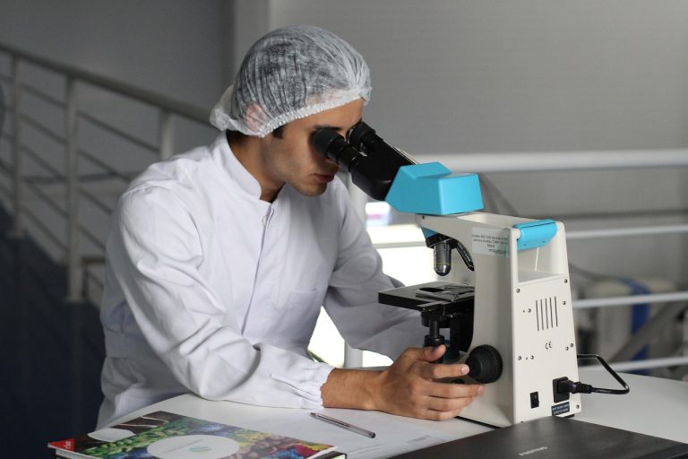 Bajaj Healthcare Q2 results: a lab scientist in a hairnet examining a sample under a microscope