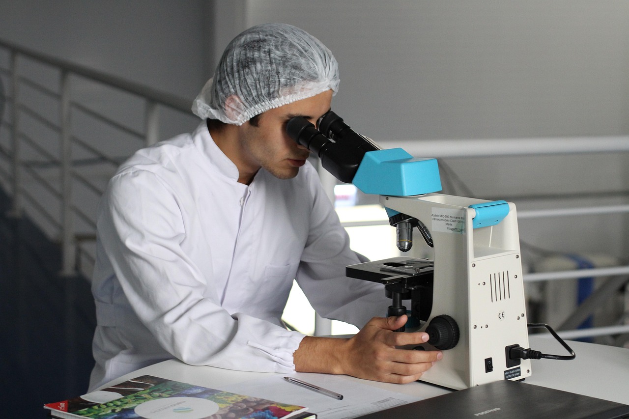 Bajaj Healthcare Q2 results: a lab scientist in a hairnet examining a sample under a microscope