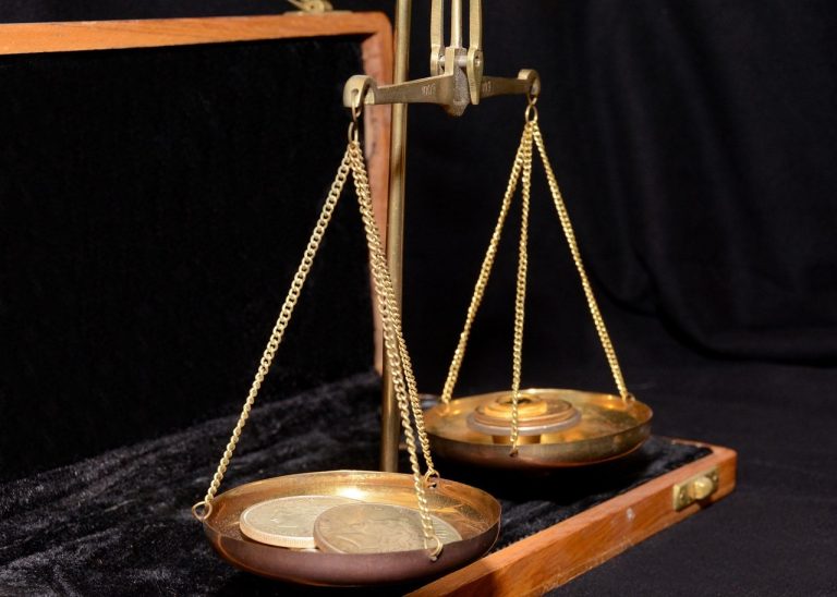 Balance of power indicator concept: a brass balance scale weighing coins against a weight