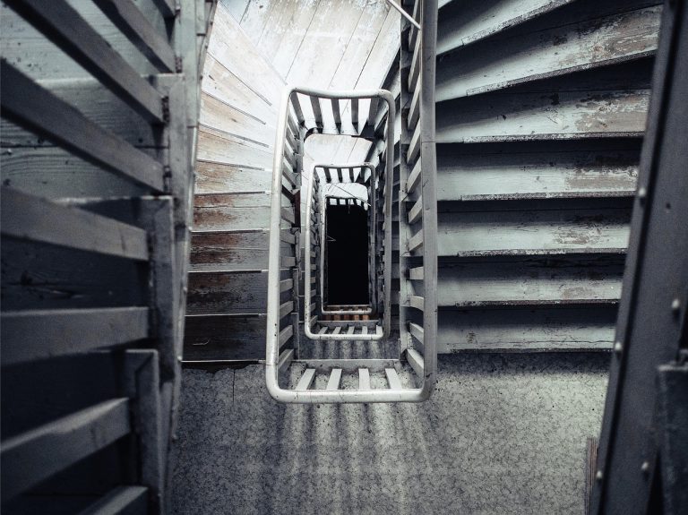 Bear put ladder concept: looking down a worn, winding stairwell from the top floor