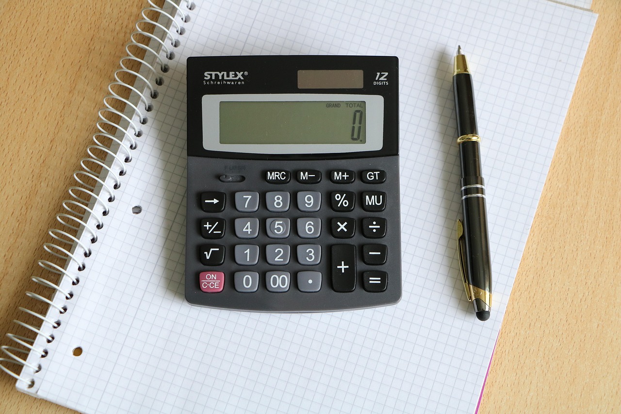 Bracket order sizing: a calculator, pen and squared notebook laid out for working out stop loss and target levels