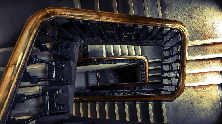 Bull call ladder options strategy: looking down a square stairwell with a wooden handrail spiralling down several floors
