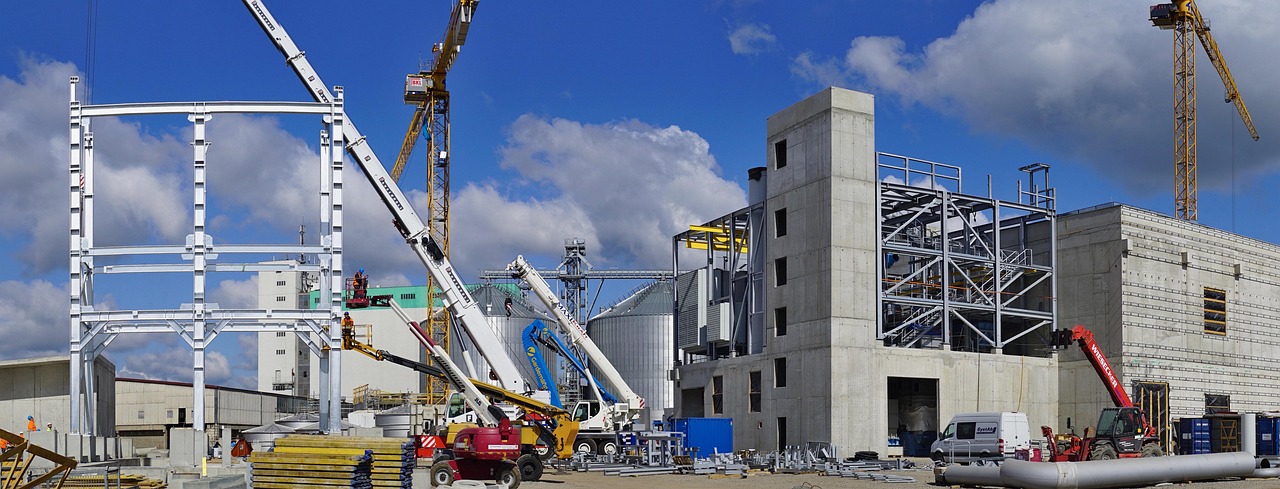 Capital work in progress meaning: an industrial plant under construction with cranes and steel frames