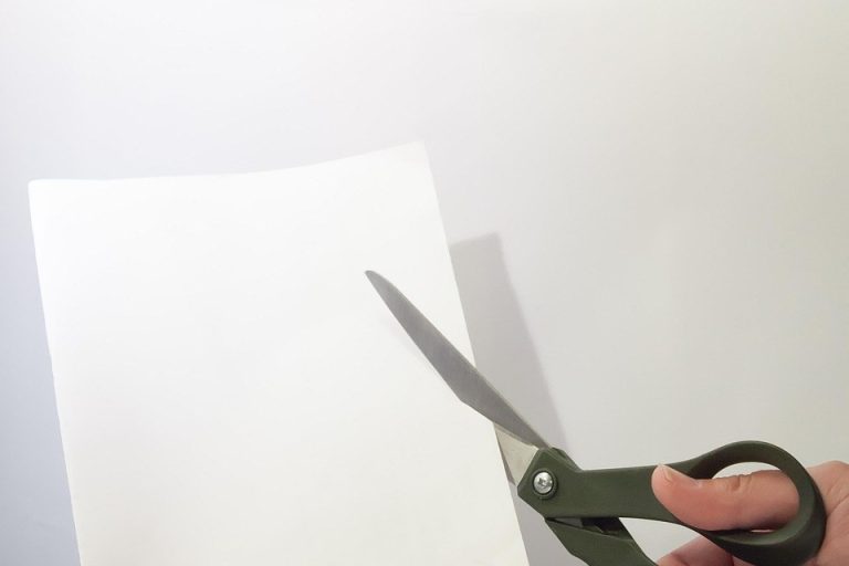 Capital reduction of shares: a hand cutting a sheet of paper with scissors