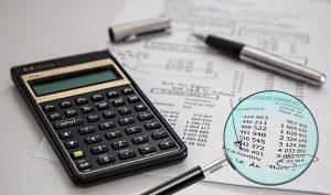 CARO report review: a magnifying glass over figures on an audit worksheet beside a calculator