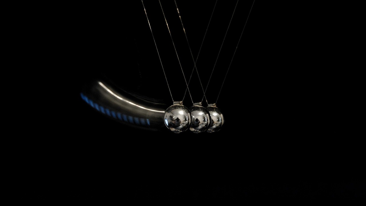 Commodity channel index concept: Newton's cradle steel balls swinging against a black background