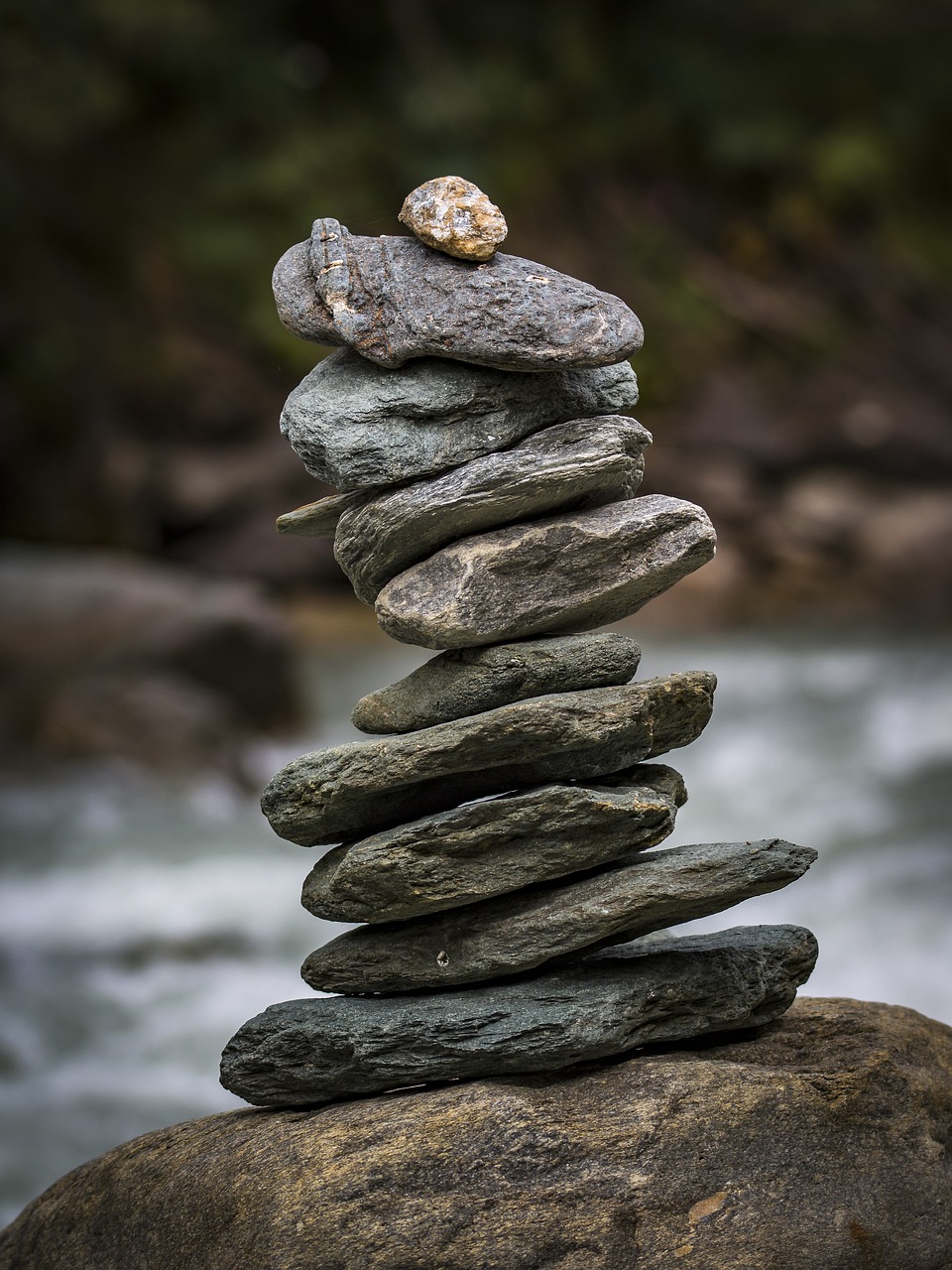 Conservative hybrid fund concept: a steady stack of flat stones balanced on a rock beside a river