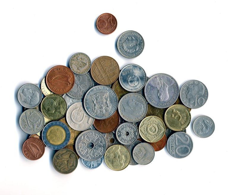 Constant currency growth meaning: a pile of old coins from many different countries on a white background