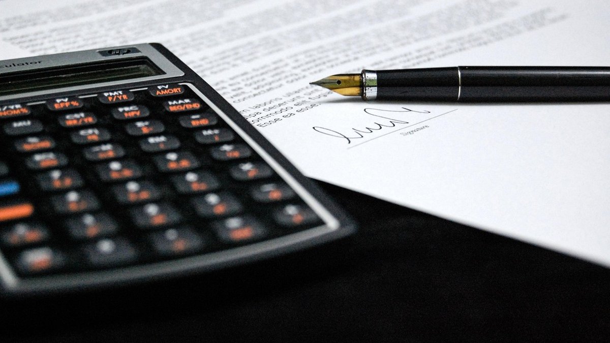 Contract note explained: a signed trade document beside a fountain pen and a financial calculator