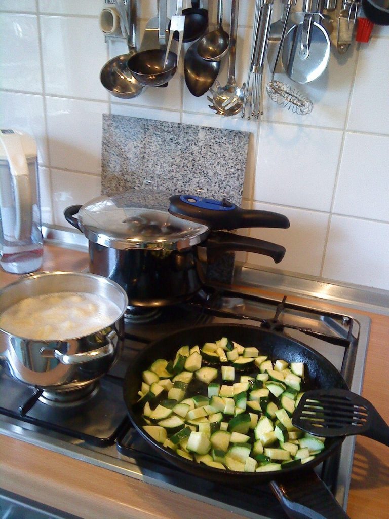 Contribution margin concept: a pressure cooker and pans cooking on a kitchen gas stove