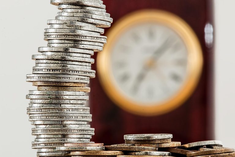 Cost of carry futures: stacked coins in front of a clock, showing the time value of money