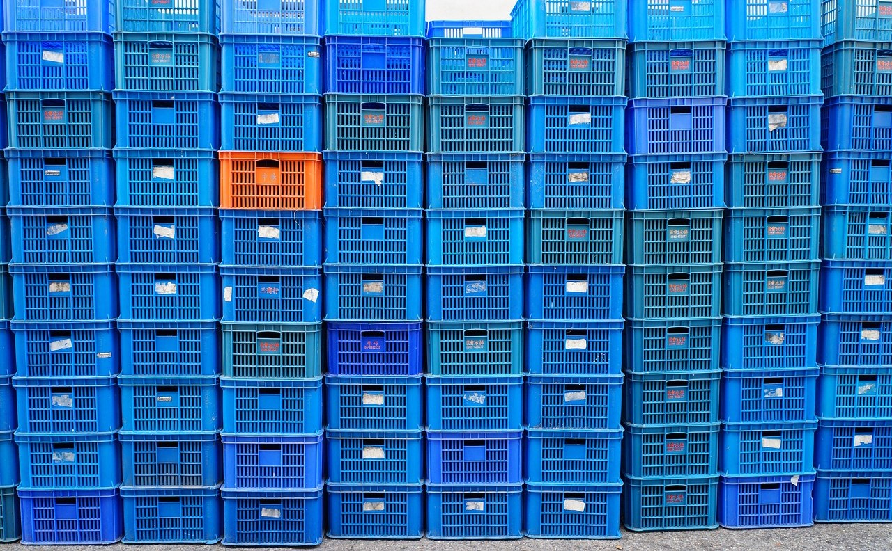 Current ratio concept: stacks of blue plastic crates with one orange crate, like inventory waiting to be sold
