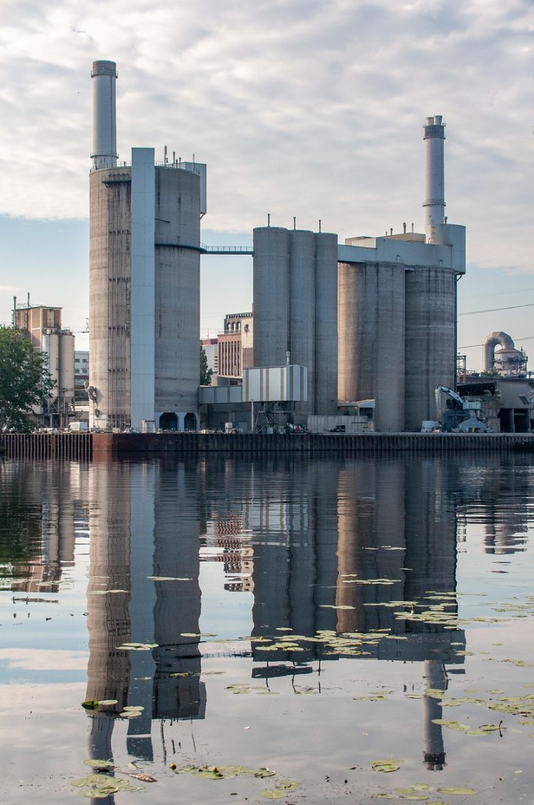 Dalmia Bharat Q2 results: cement plant silos and chimneys by the water