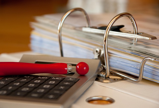 Days payable outstanding: a ring binder full of supplier invoices beside a calculator and red pen