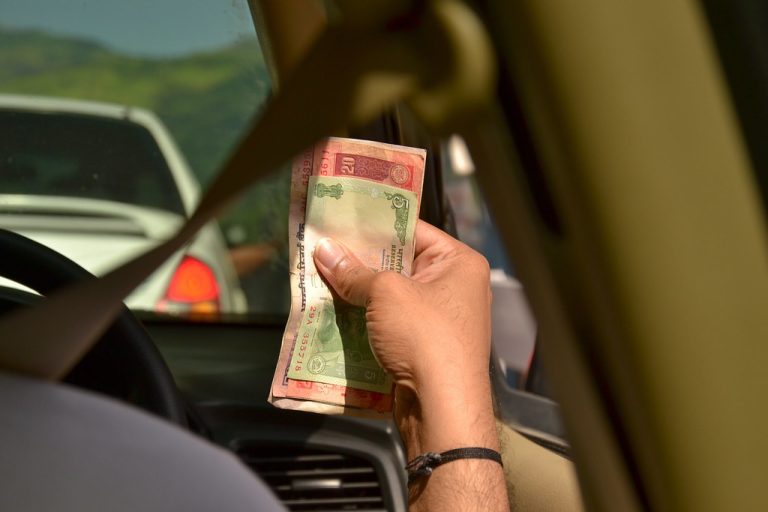 DCB Bank Q2 results: a hand holding Indian rupee notes inside a car