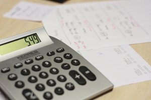Debtor days in company results: a calculator beside a stack of unpaid invoices on a desk