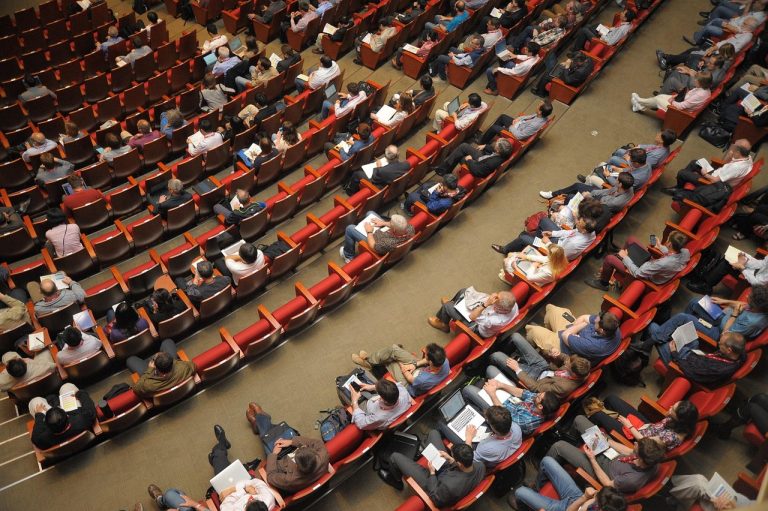Delisting of shares: shareholders seated in a large auditorium during a company meeting