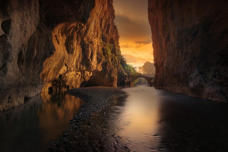 Donchian channel indicator: a river flowing through a narrow channel between tall canyon walls at sunset