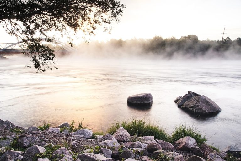 Double diagonal spread idea: a calm river flowing between two rocky banks at dawn