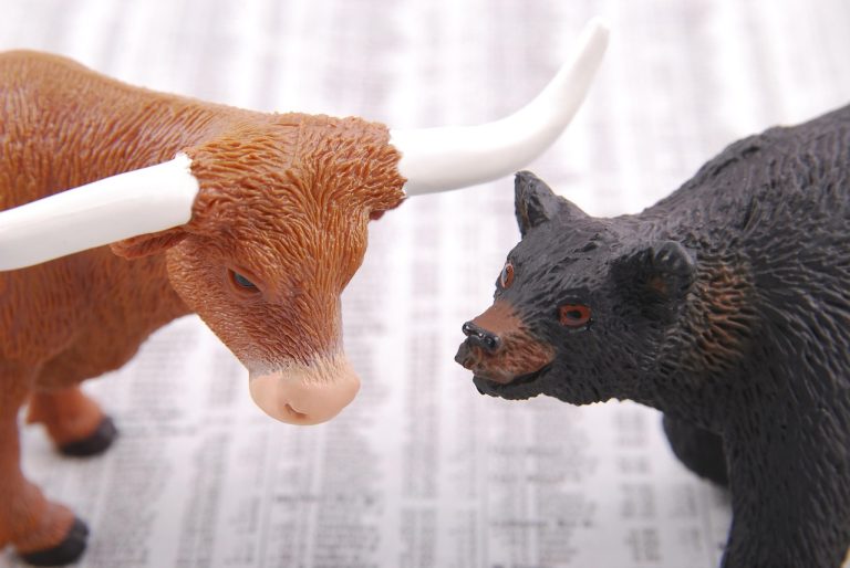 Elder Ray Index: toy bull and bear figures facing each other on a newspaper stock listings page