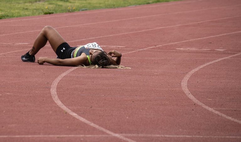 Exhaustion gap concept: a tired runner lying flat on a red athletics track after a race