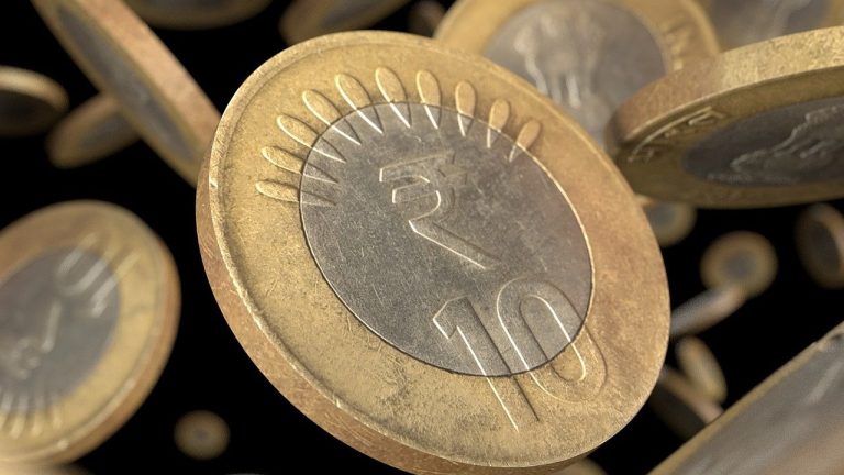 Face value of share concept: Indian ten-rupee coins falling against a dark background