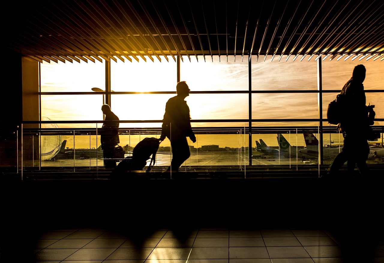 FPI outflow October 2026: silhouetted travellers wheeling suitcases out through an airport terminal at sunset