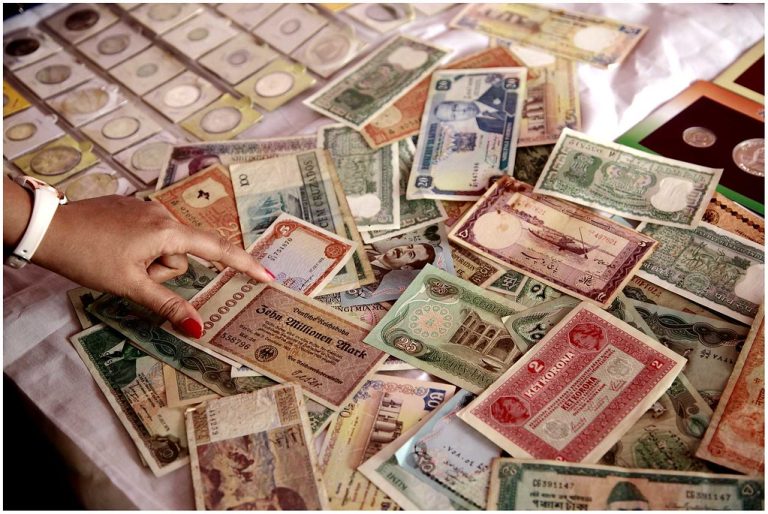 FPI selling: a hand pointing at banknotes from many countries spread across a table