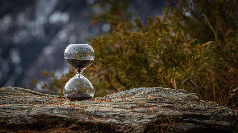 10 year constant maturity gilt fund concept: an hourglass with dark sand resting on a weathered rock