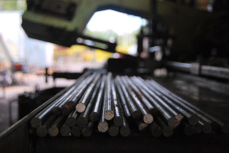 Gross margin meaning concept: a bundle of cut steel rods on a factory saw bed, the kind of raw material that drives a manufacturer's costs