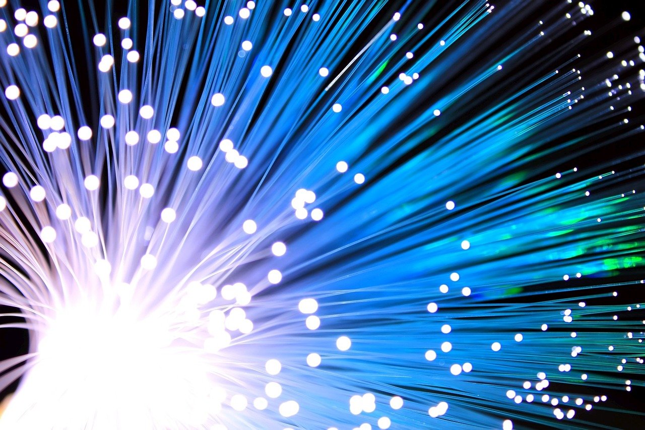 HFCL Q2 results: glowing blue optical fibre strands spreading out against a dark background