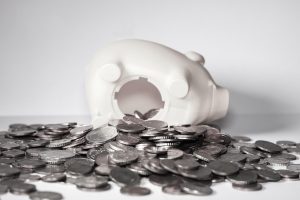 IDCW option in mutual fund: coins spilling out of an upturned white piggy bank