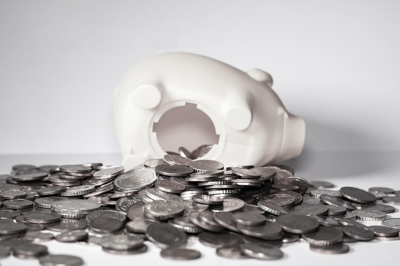IDCW option in mutual fund: coins spilling out of an upturned white piggy bank