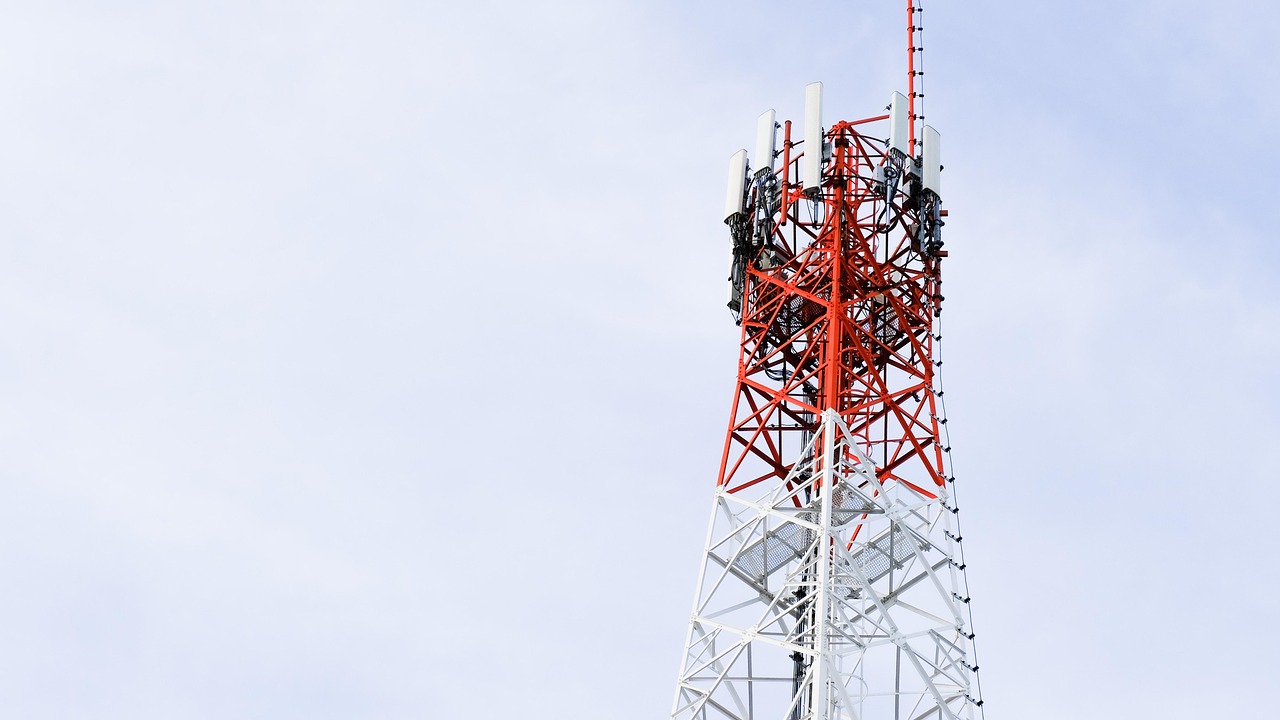 Jio Platforms IPO issue price: red and white mobile telecom tower with network antennas against a pale sky